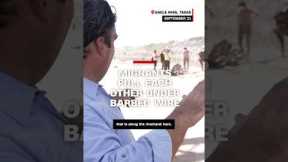 Migrants pull each other under barbed wire
